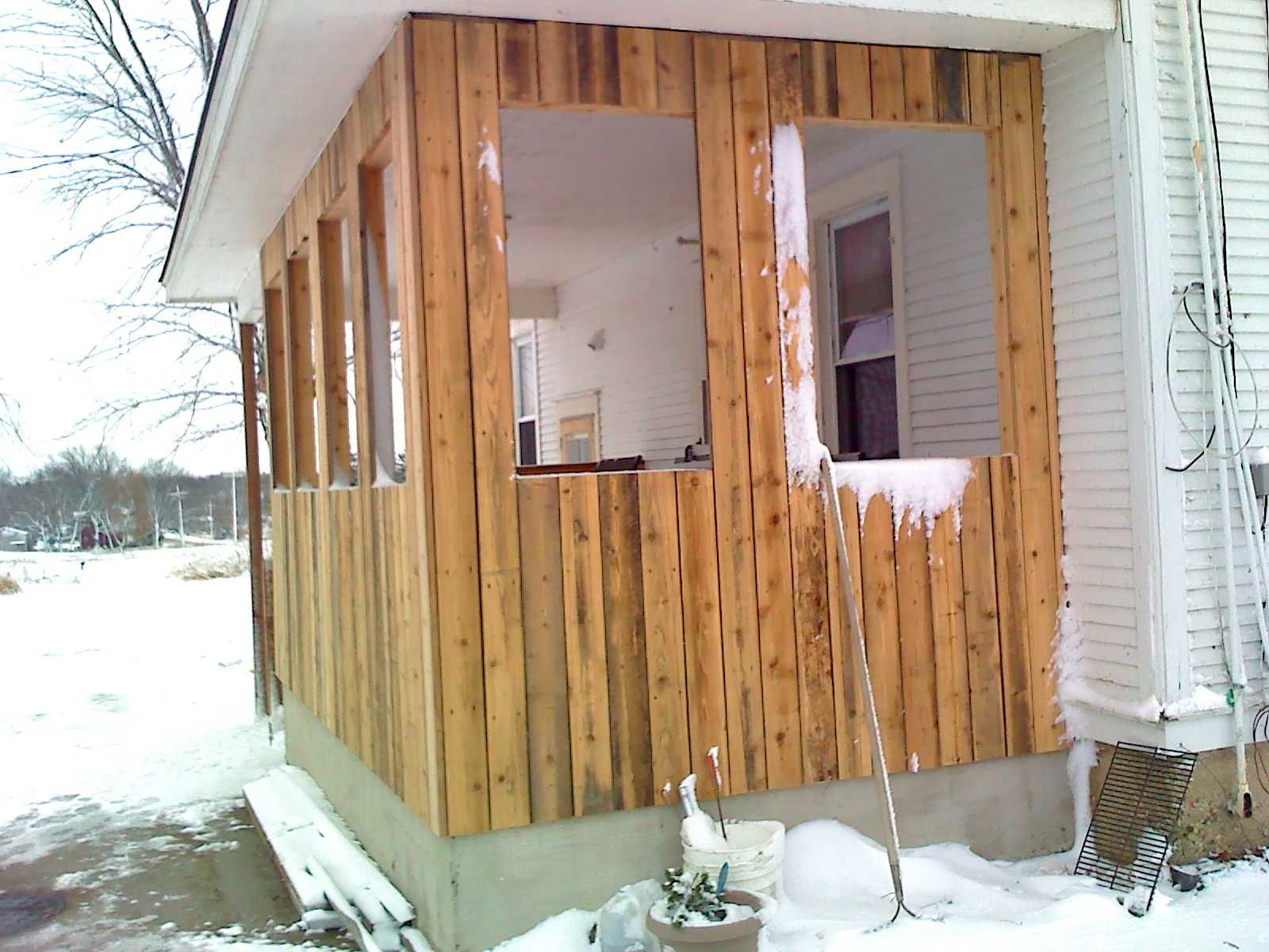 A house with a wooden porch and a window covered in snow