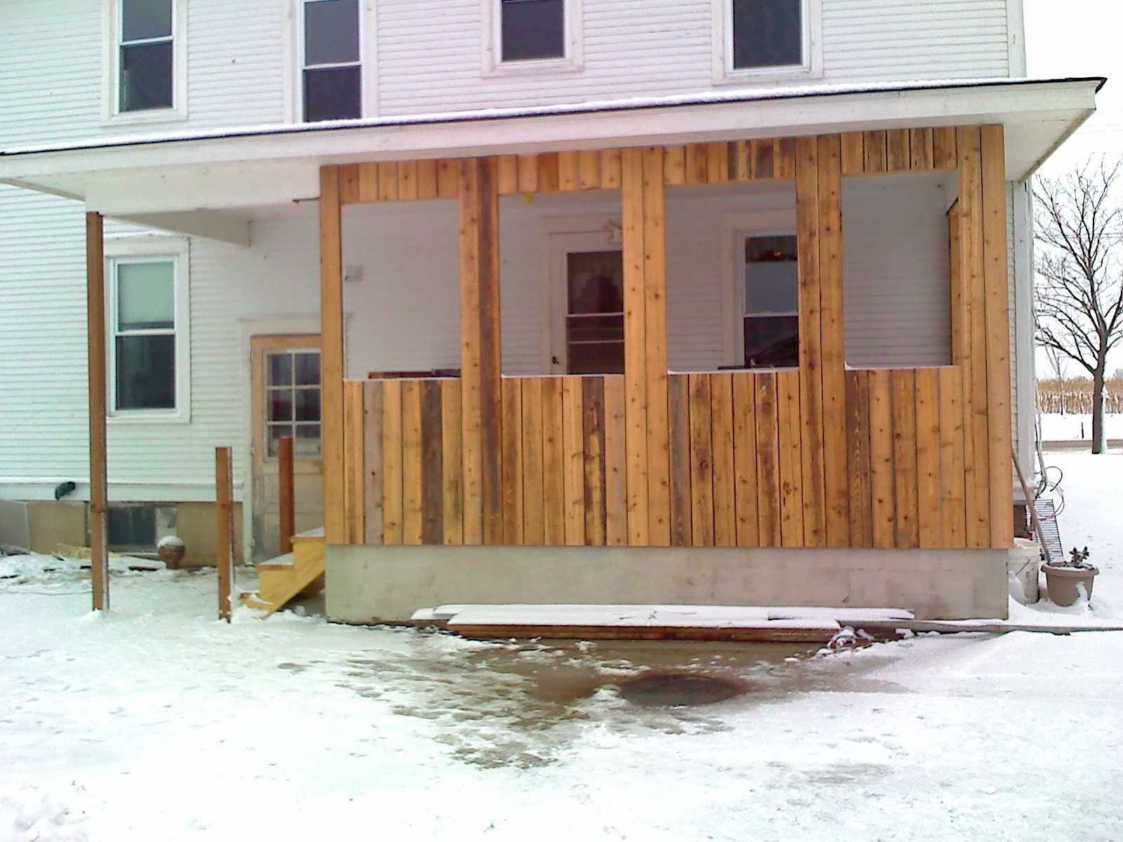 A white house with a wooden porch in the snow
