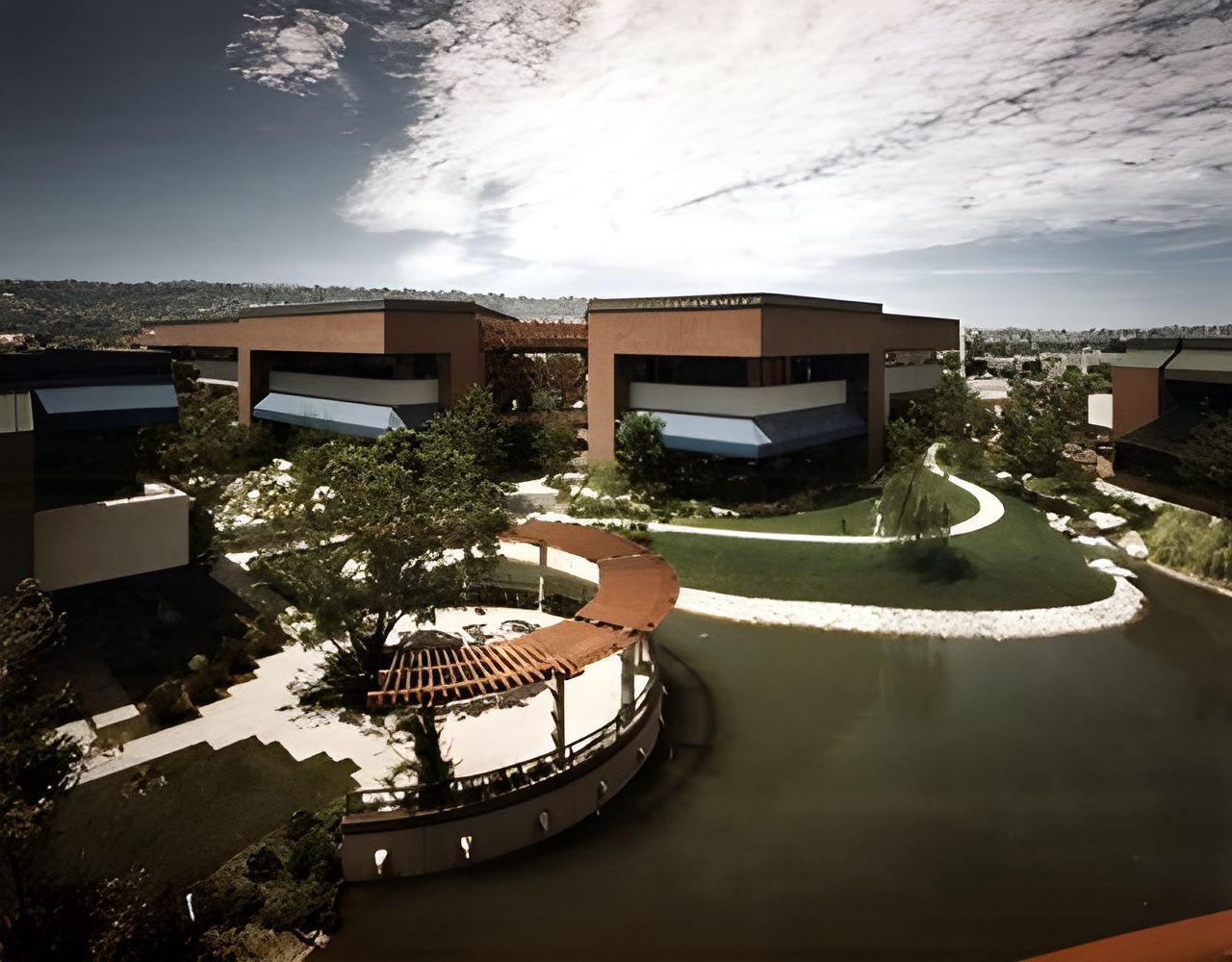 An aerial view of a building with a pond in front of it