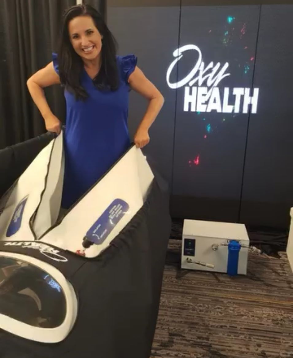 A woman is laying on a bed with a clear dome over her head.