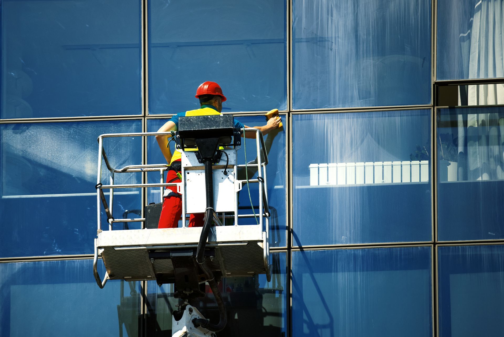Pulizia vetrate di edifici con carrello elevatore