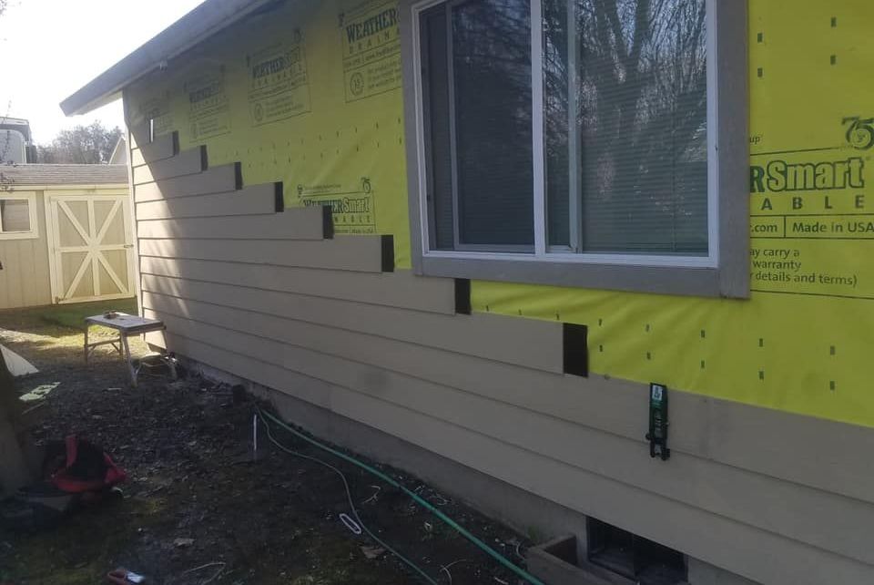 A house is being remodeled with siding and a window.