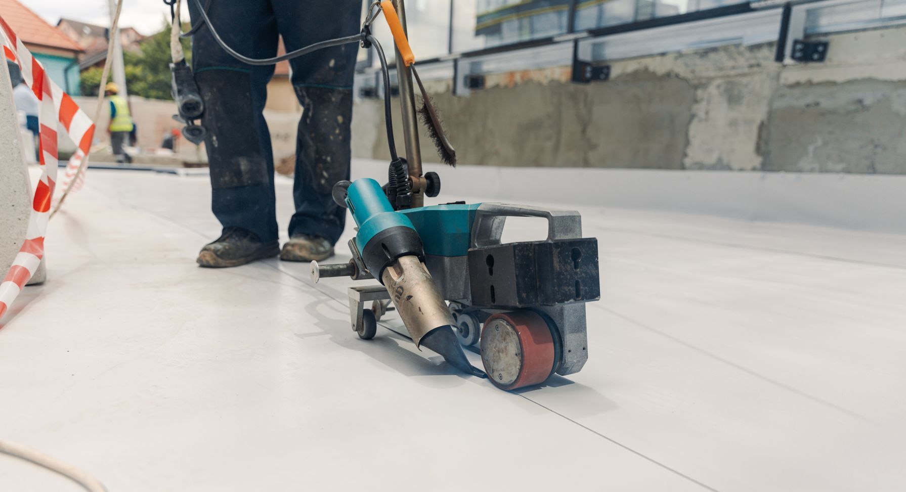 A man is using a machine to seal a roof.