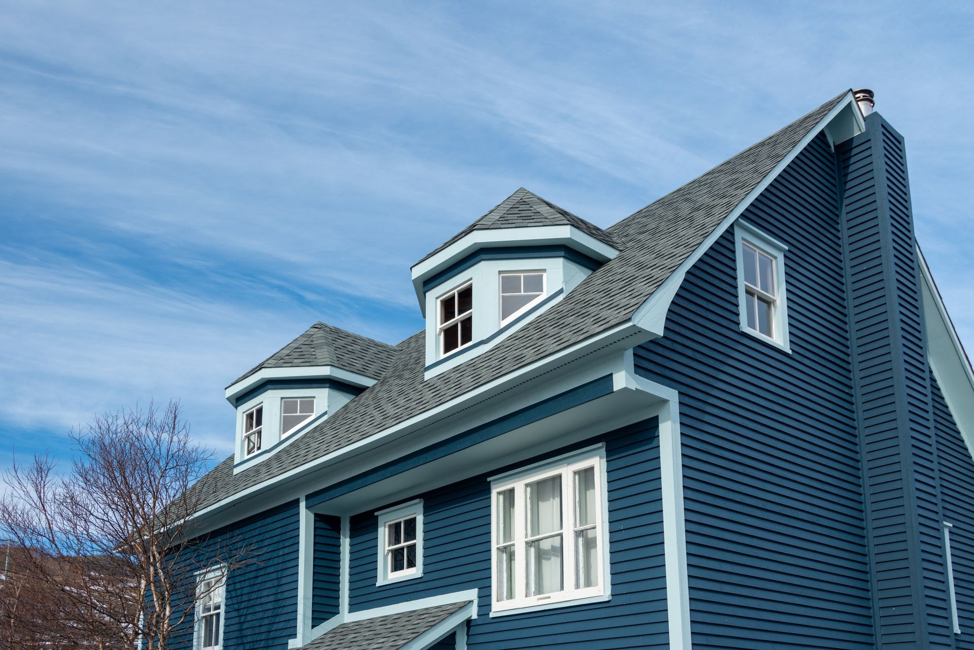 A large blue house with a gray roof and white trim.