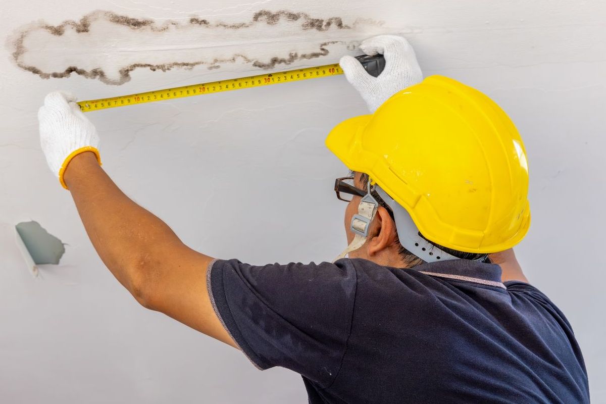 A man is measuring a wall with a tape measure.