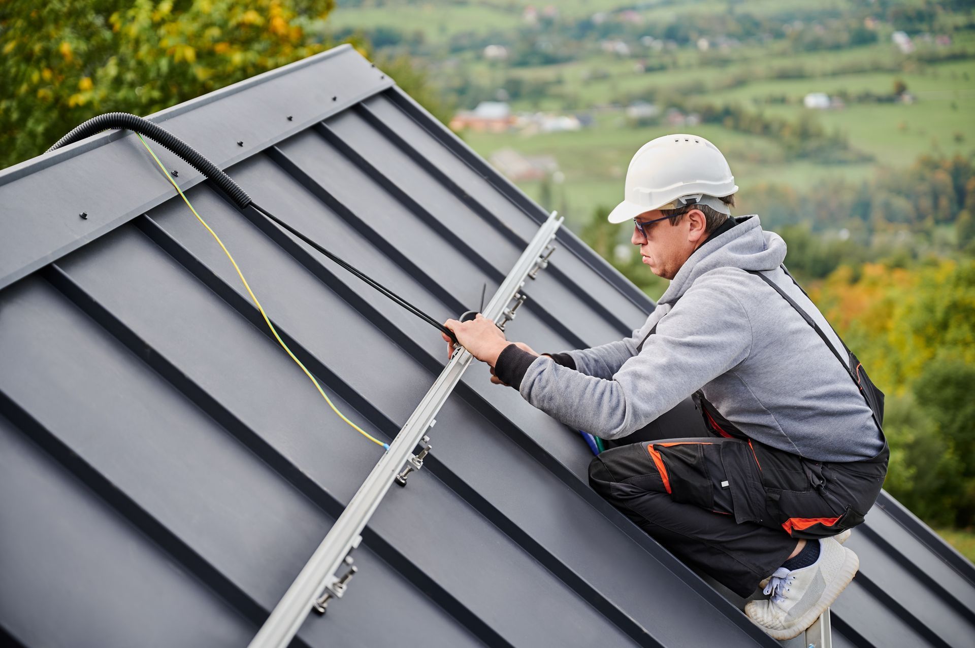 A man is installing solar panels on the roof of a house.