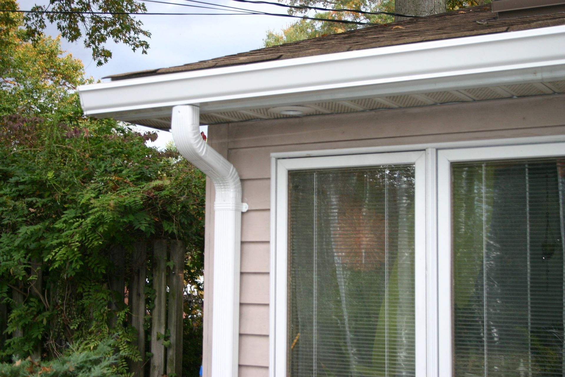 A person is installing a gutter on the roof of a house.