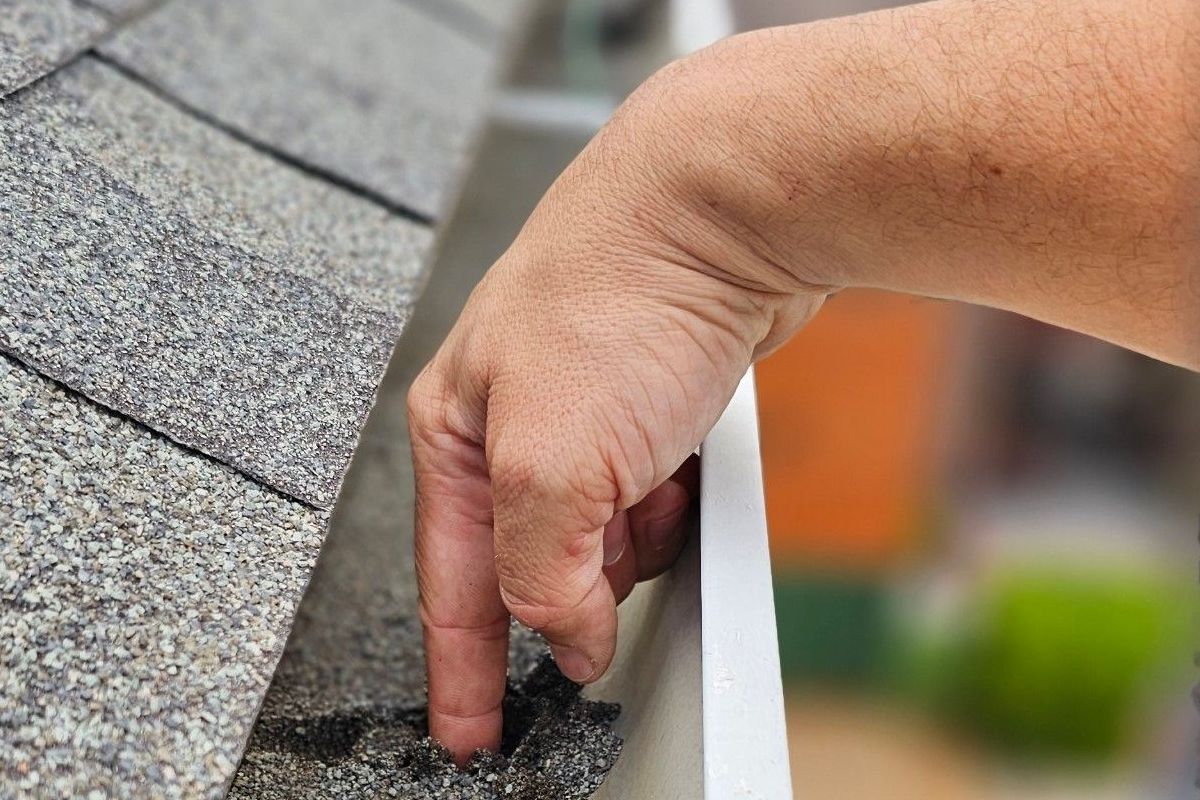 A person is cleaning a gutter on a roof.