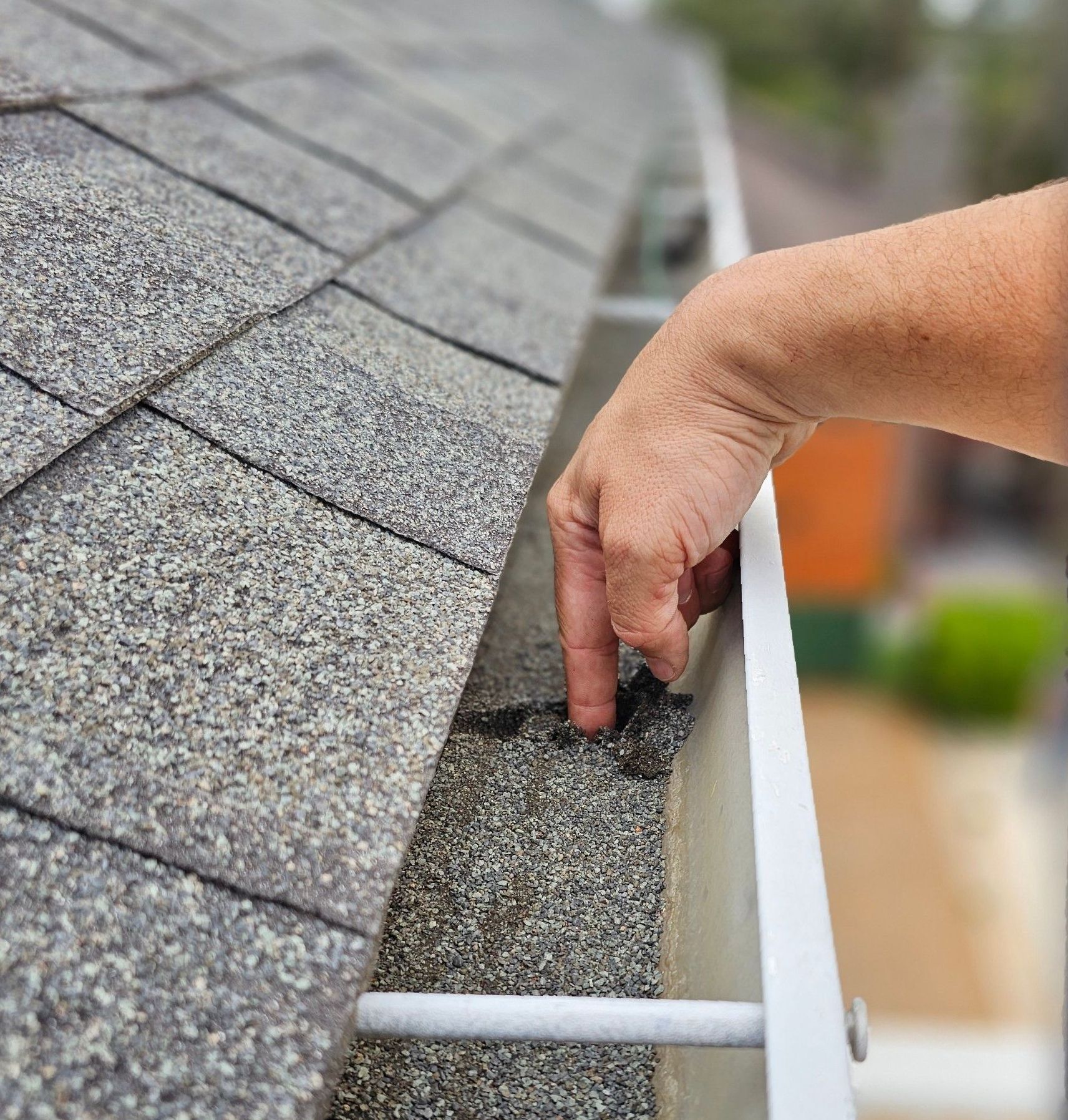 A person is cleaning a gutter on a roof.