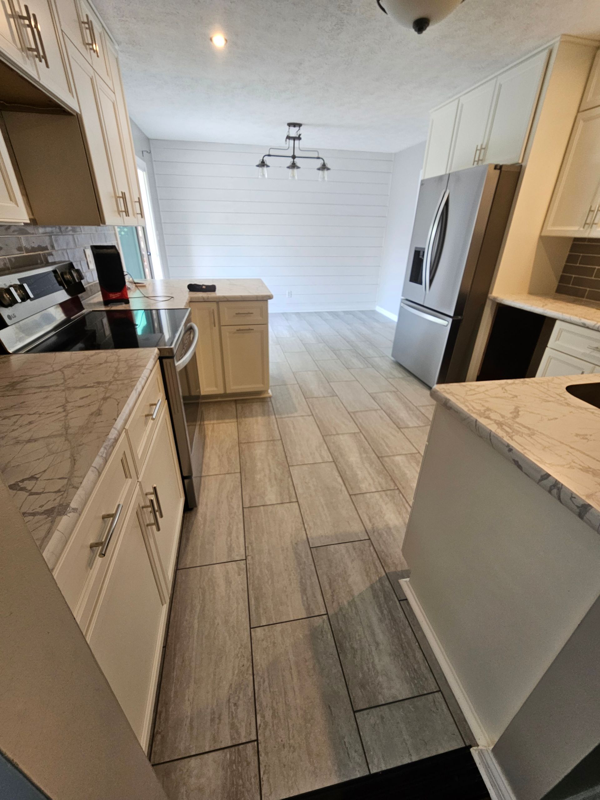 Kitchen with light wood-look floor, white cabinets, and stainless steel appliances.