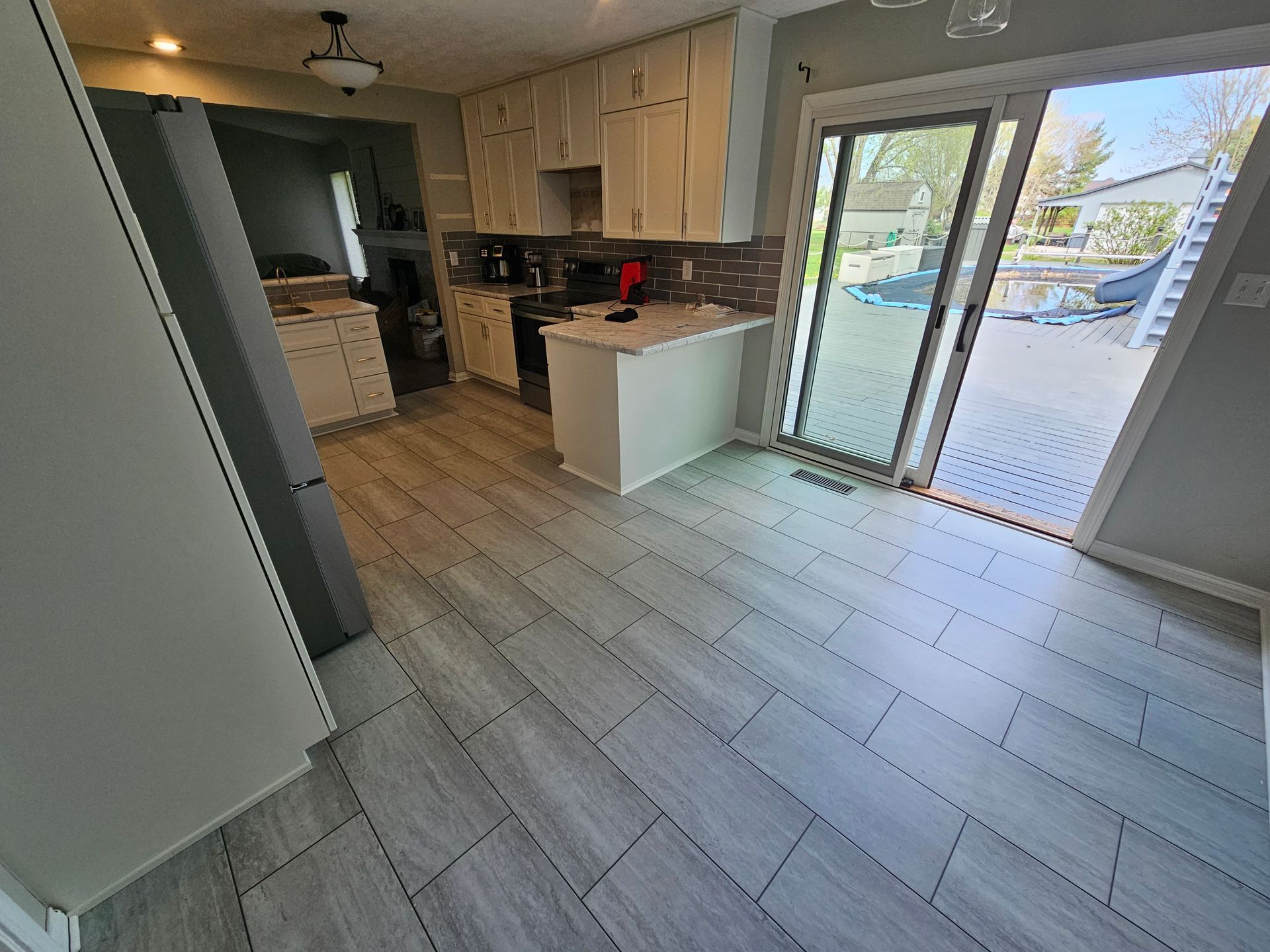 Kitchen with light gray tile flooring, white cabinets, and a sliding door to a deck.