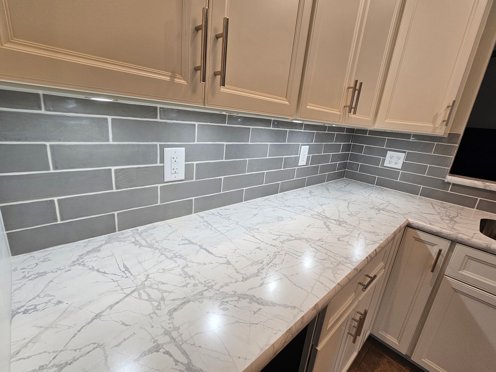 Kitchen with white cabinets, gray subway tile backsplash, and white countertop.