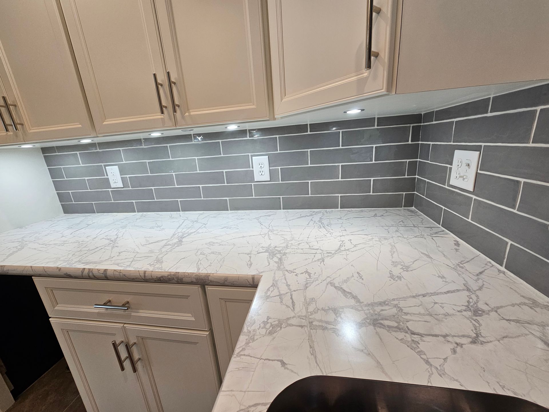 Kitchen with white cabinets, gray subway tile backsplash, and white quartz countertop.