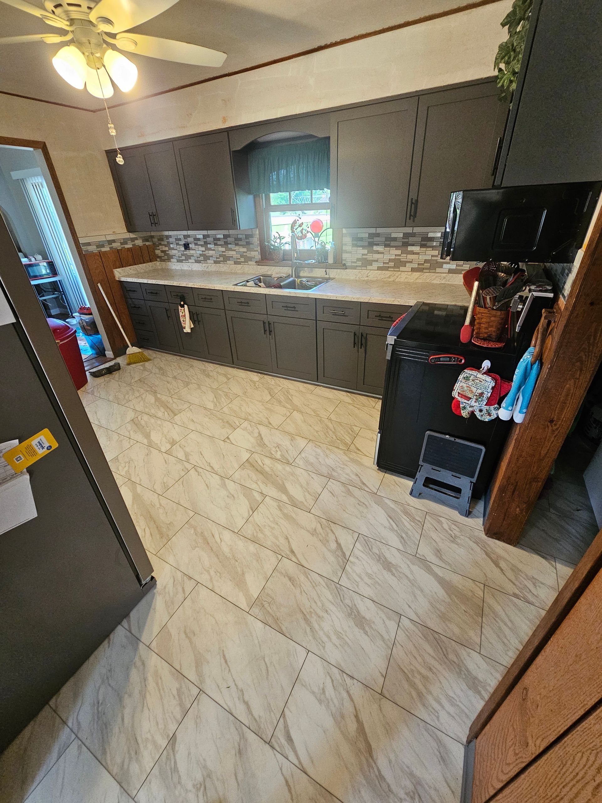Kitchen interior with dark cabinets, light countertops, and wood-look flooring.
