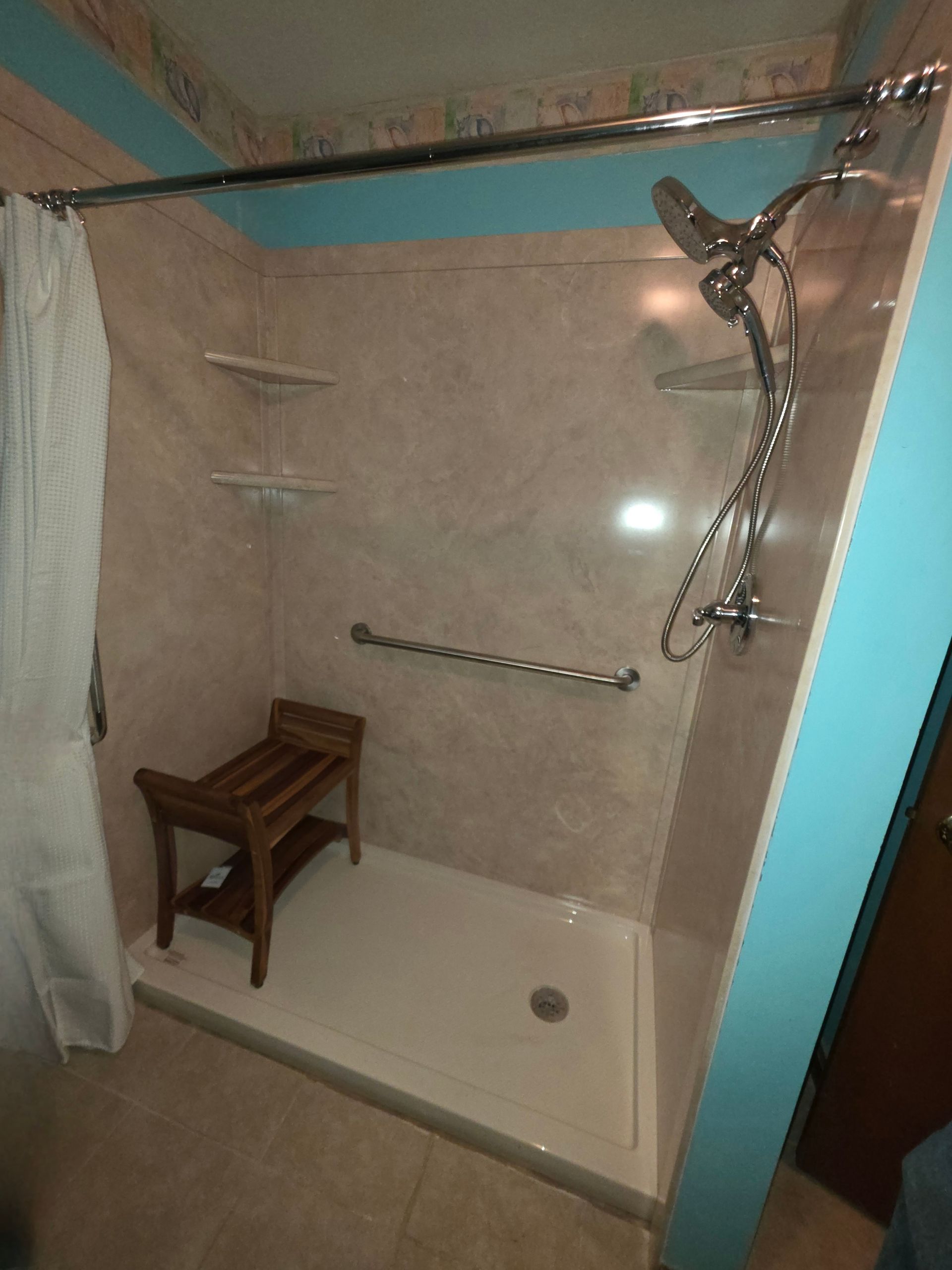 Shower stall with grab bar, shower seat, and adjustable showerhead.