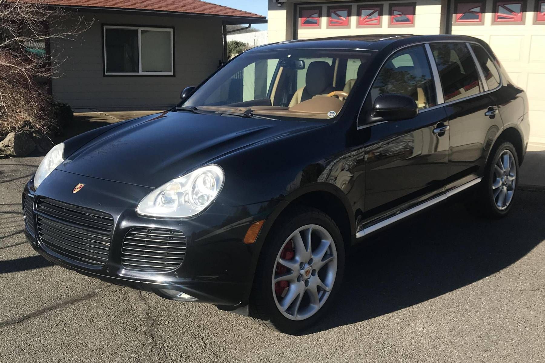 Zwarte Porsche SUV geparkeerd op het trottoir, met rode remklauwen.