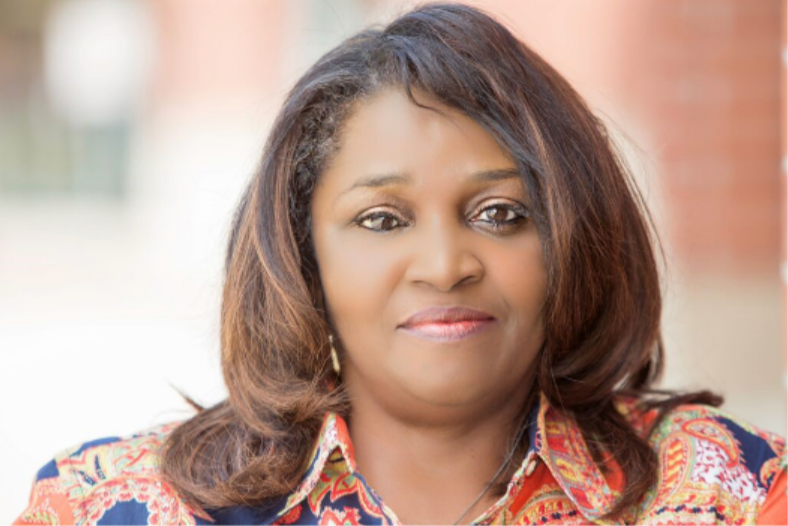 A woman in a colorful shirt is smiling for the camera.