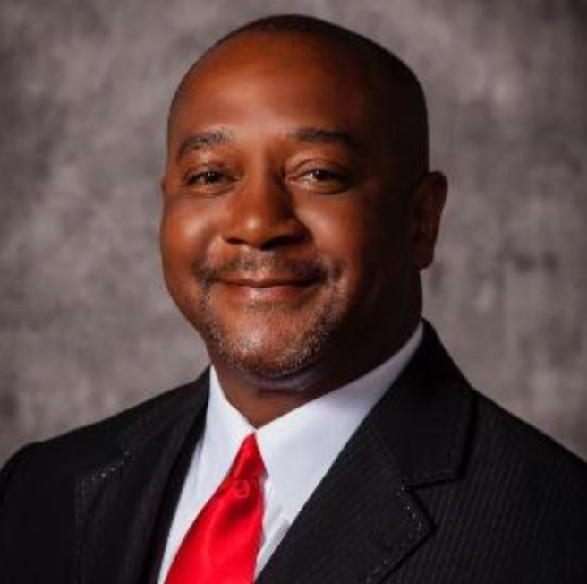 A man in a suit and red tie is smiling for the camera.