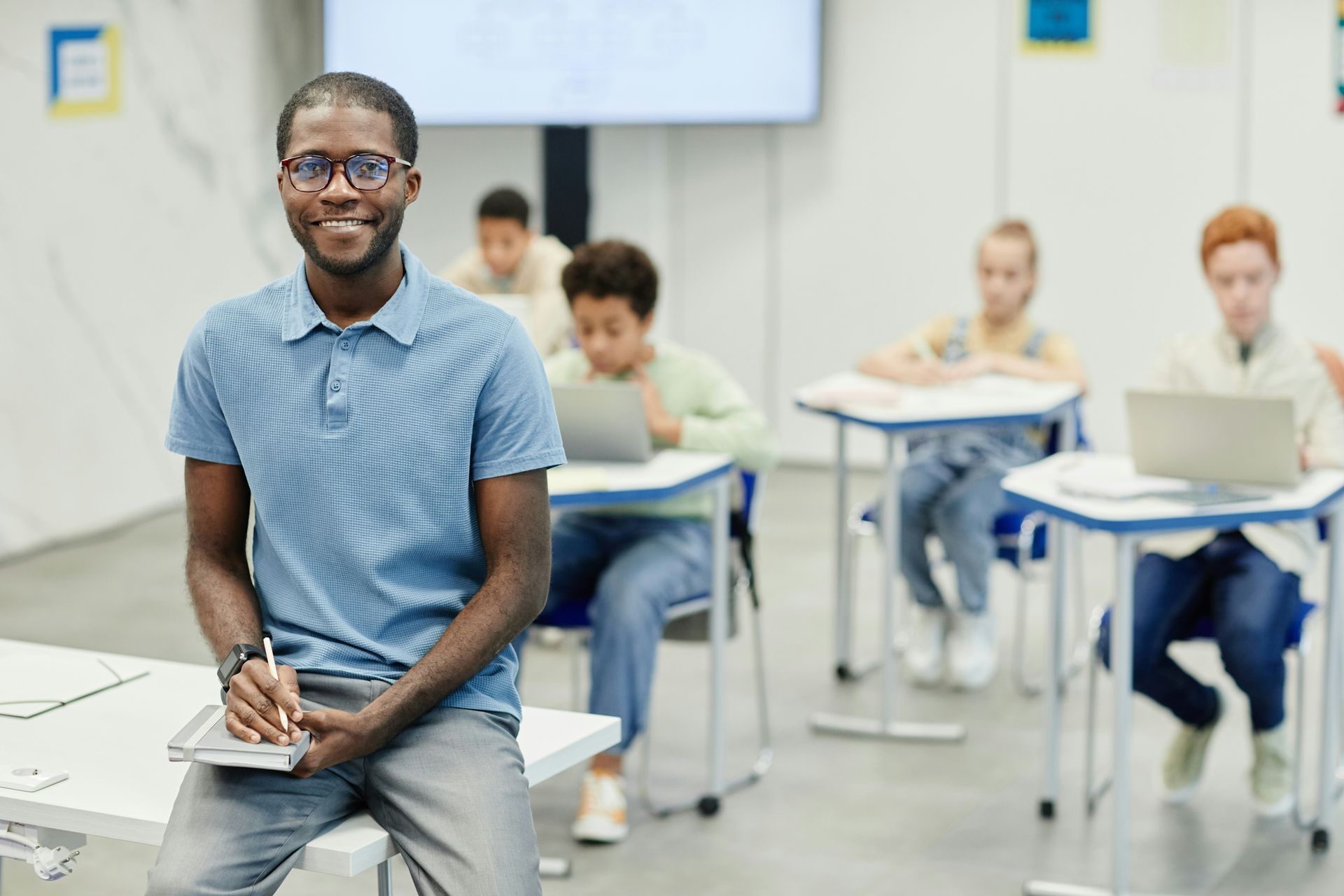 A man is sitting in front of a classroom full of students.