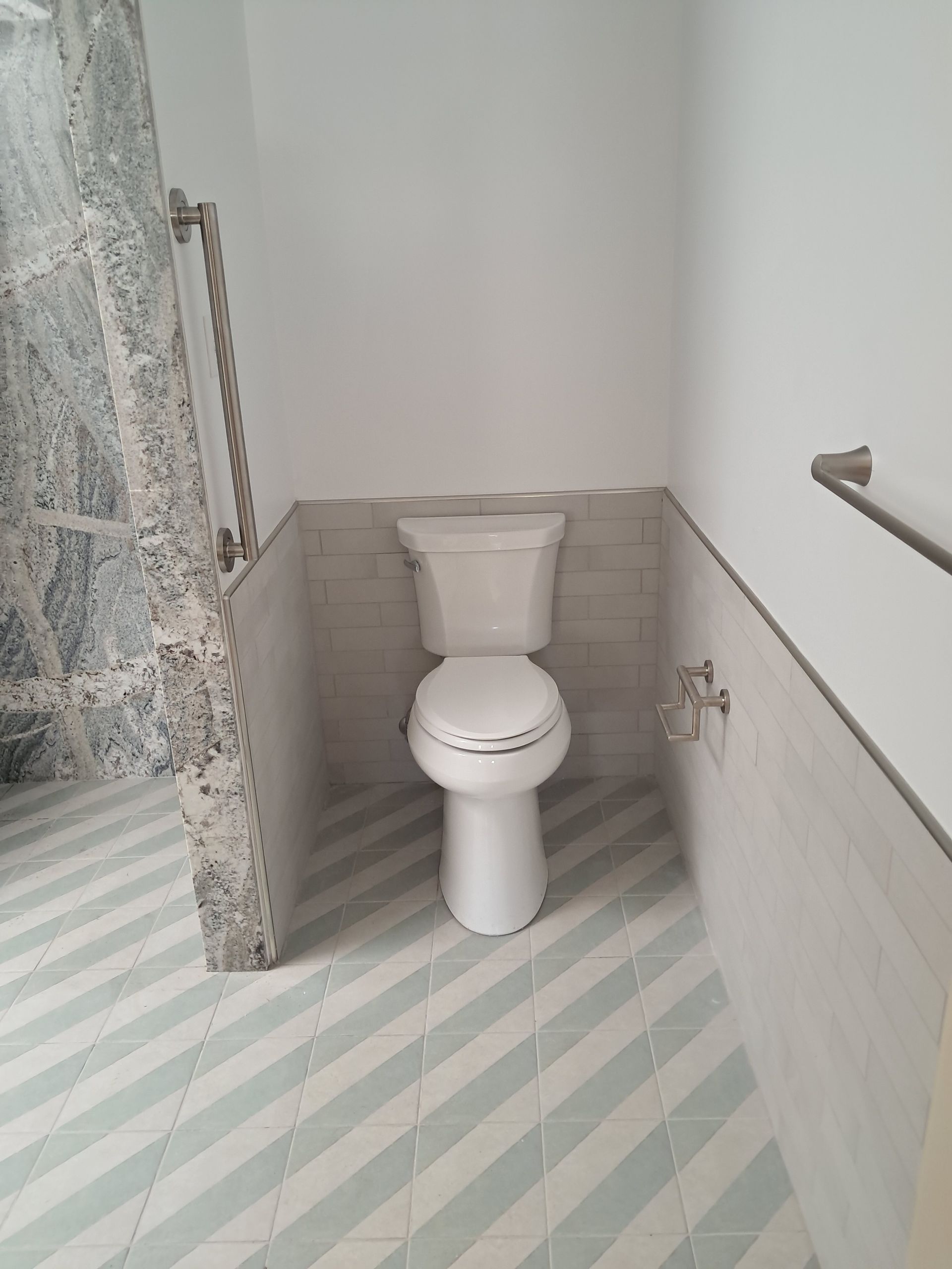 Plumber in black gloves using a red wrench under a bathroom sink.