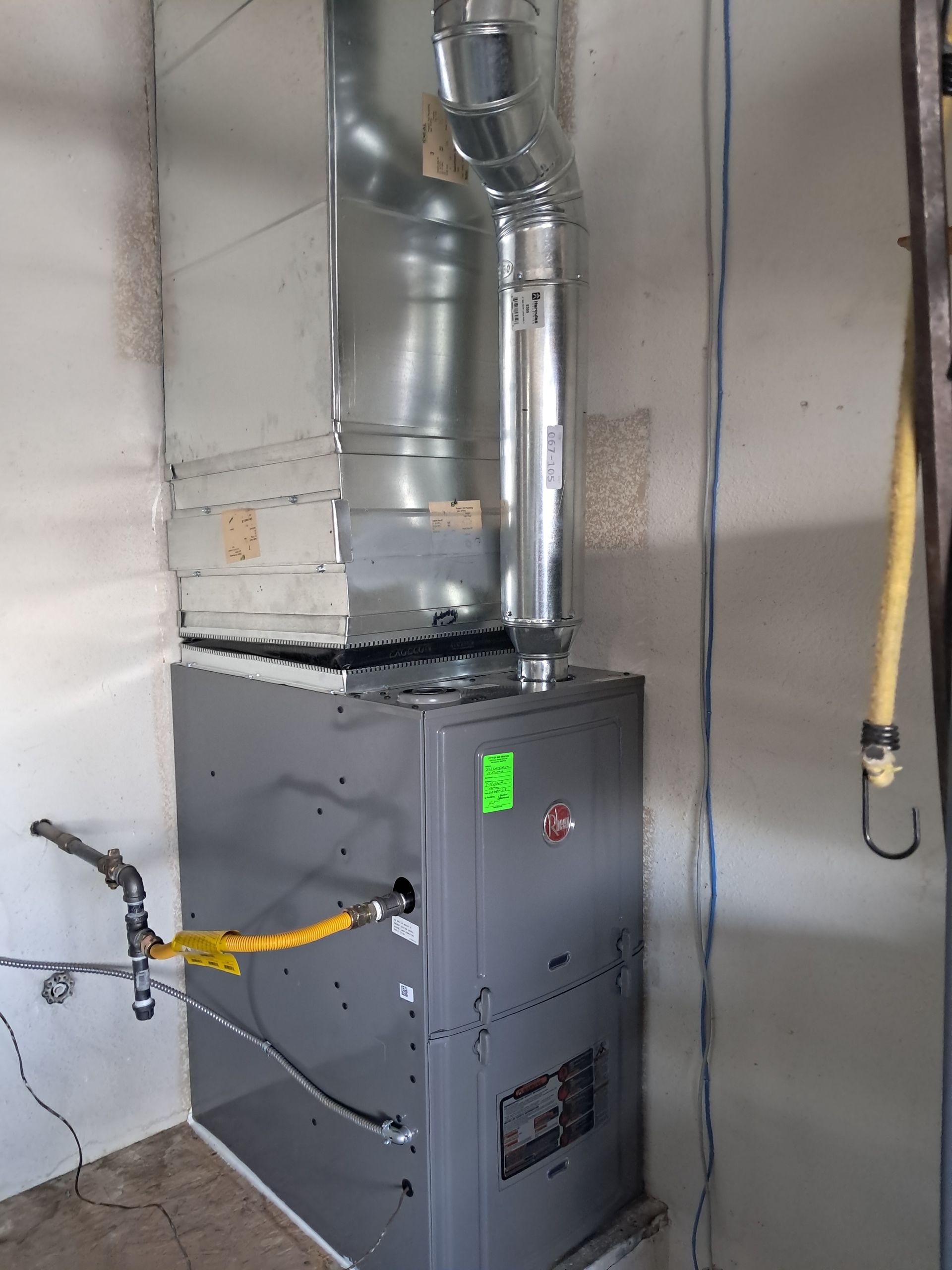 Tankless water heater mounted on a wall, with gas and water lines connected.