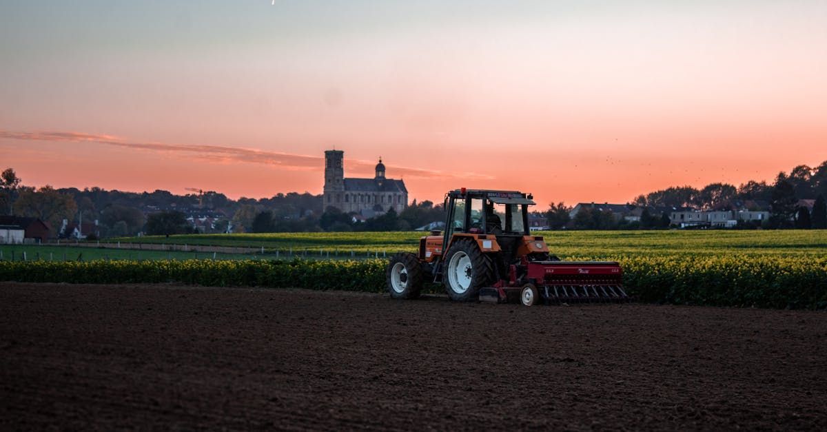 A tractor is plowing a field at sunset.