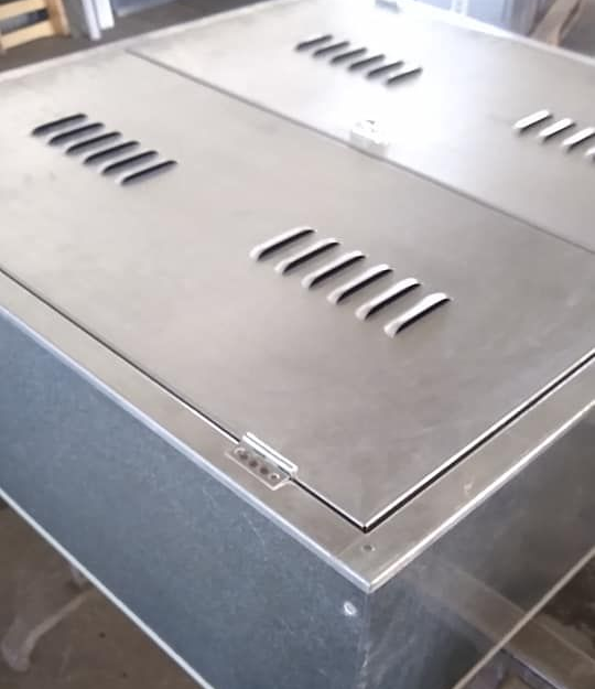 Una ripresa ravvicinata e dall'alto di un contenitore metallico quadrato con prese d'aria a lamelle sul pannello superiore incernierato.