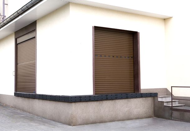 Posto auto coperto aperto con scaffali, una bicicletta, un piccolo trattore giocattolo giallo e attrezzi su un pavimento di cemento rosso.