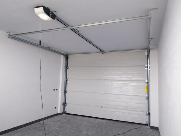 Porta da garage sezionale bianca all'interno di un garage con apriporta automatico montato a soffitto.