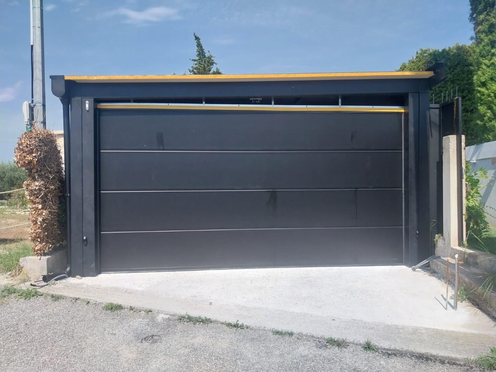Una moderna porta da garage nera con pannelli orizzontali incastonati in una cornice scura su un vialetto di cemento all'esterno.