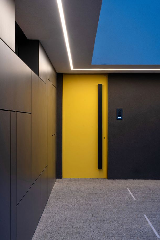 Primo piano di una porta d'ingresso in legno scuro con ferramenta cromata, tra cui serratura, catenaccio e spioncino.