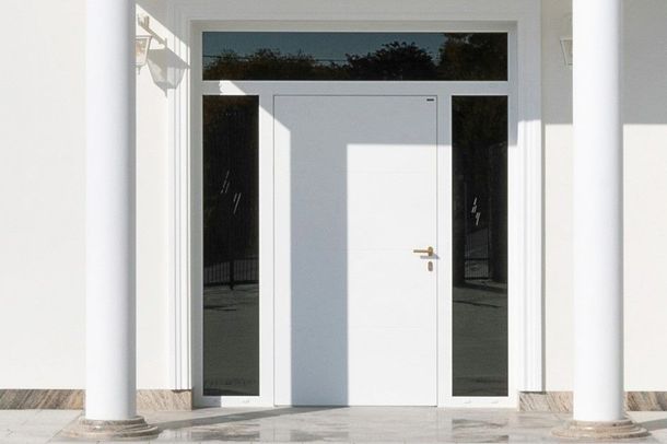 Una porta di legno marrone scuro è leggermente socchiusa, con un meccanismo di chiusura metallico e le chiavi nella serratura.