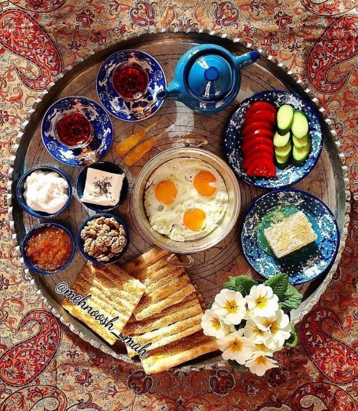 A tray filled with plates of food and a teapot on a rug.