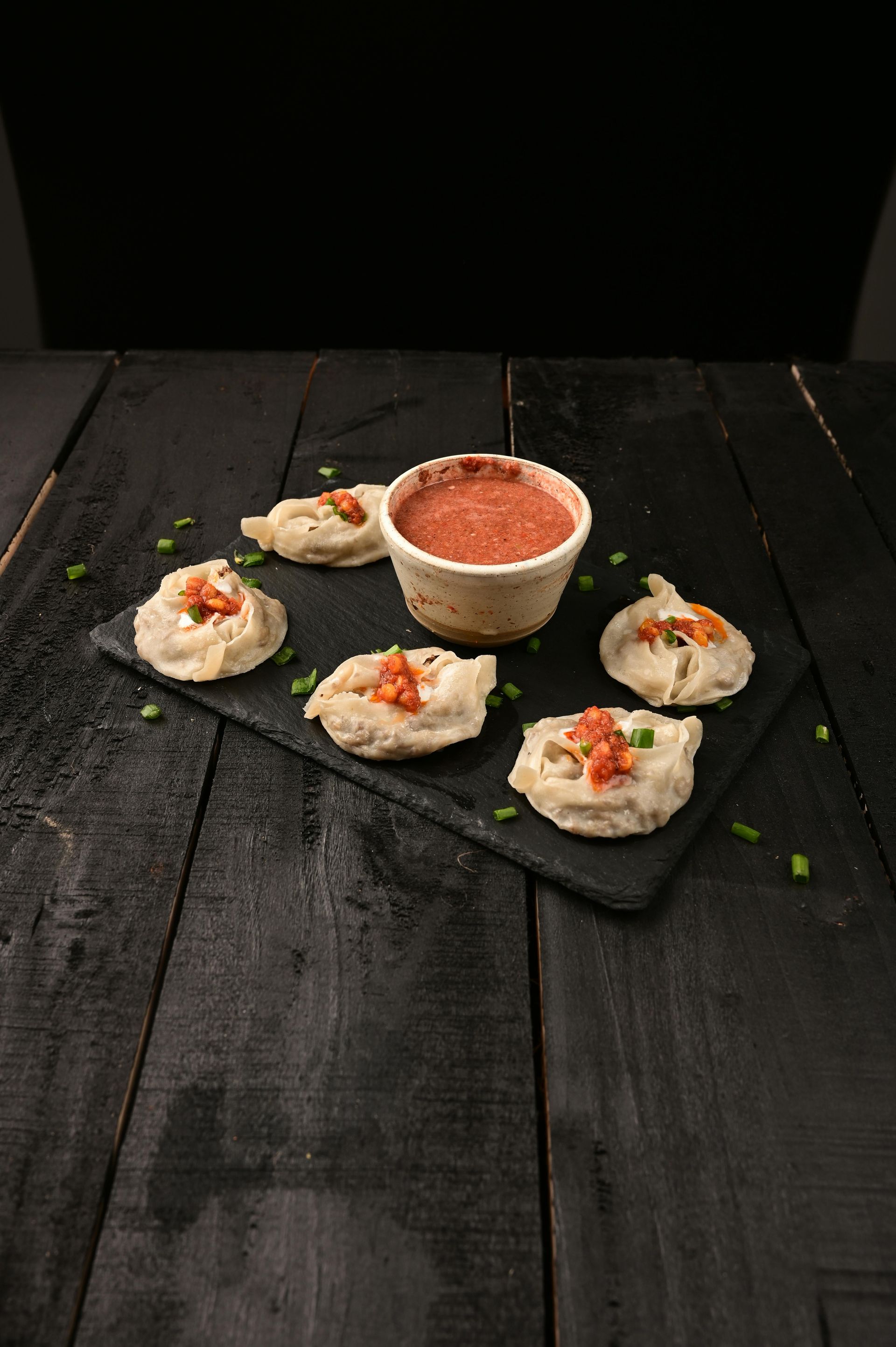 A plate of food with a bowl of sauce on a wooden table.