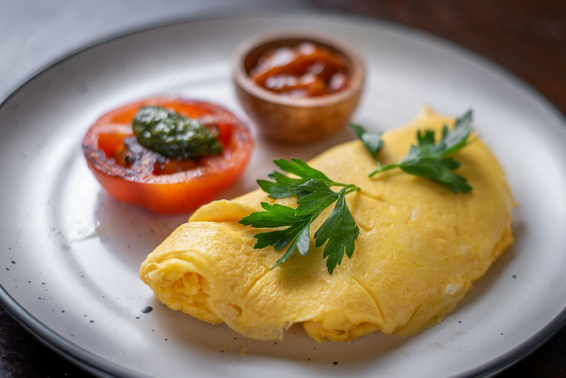 A white plate topped with an omelet and tomatoes.