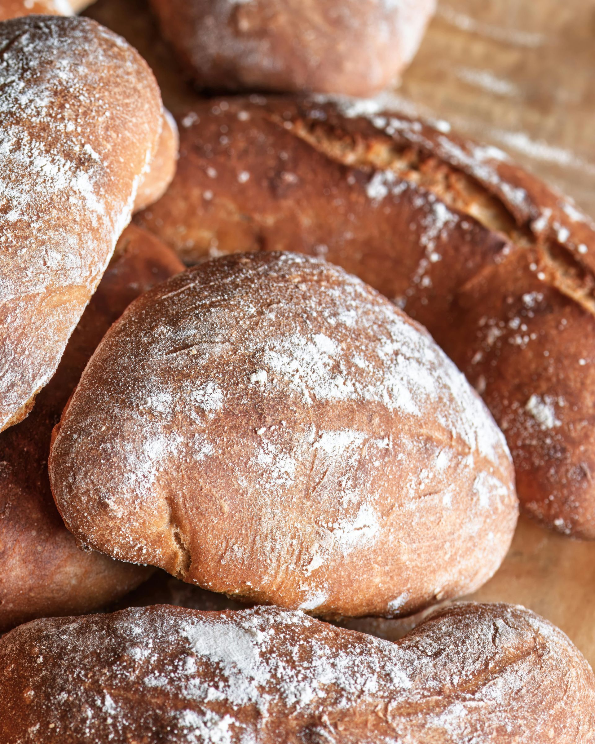 A pile of bread rolls covered in powdered sugar on a table.