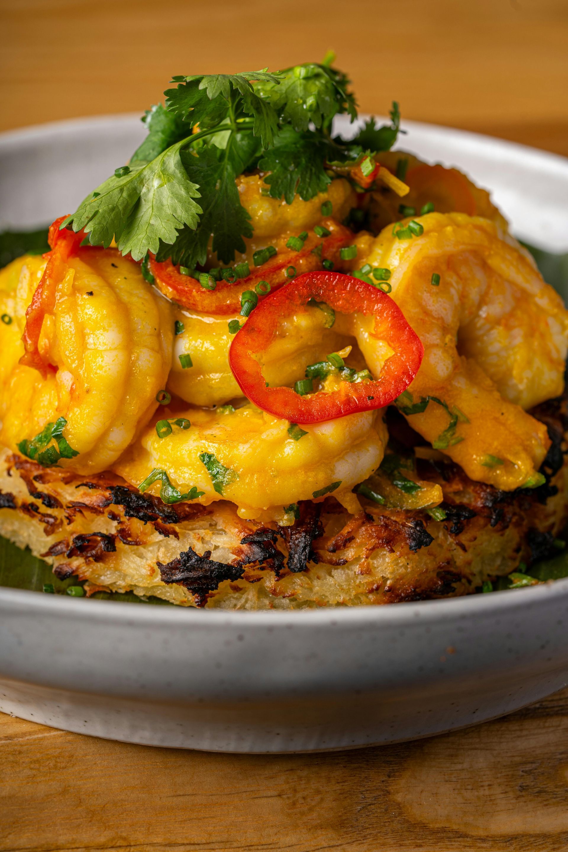 A close up of a plate of food with shrimp and vegetables on a table.