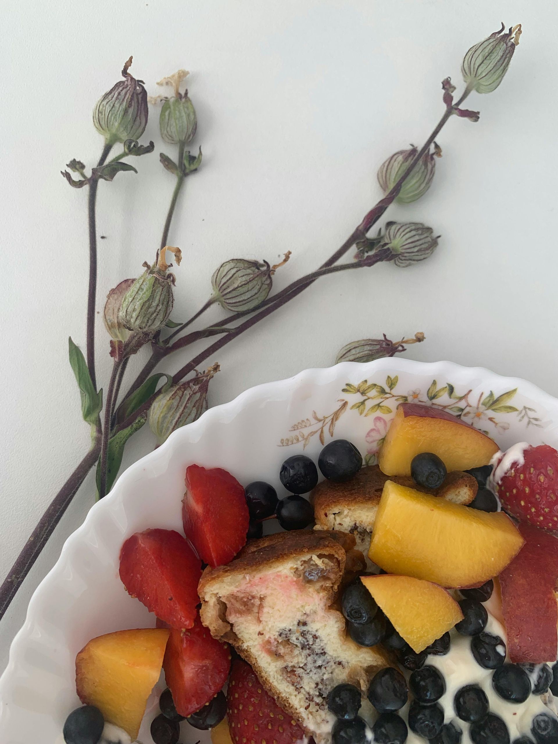 A white plate topped with strawberries blueberries and peaches