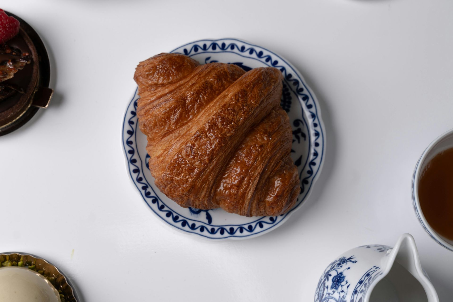 A croissant is on a blue and white plate on a table.