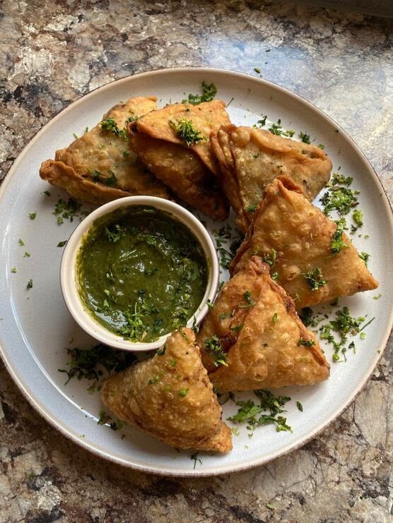 A white plate topped with fried food and a bowl of dipping sauce.