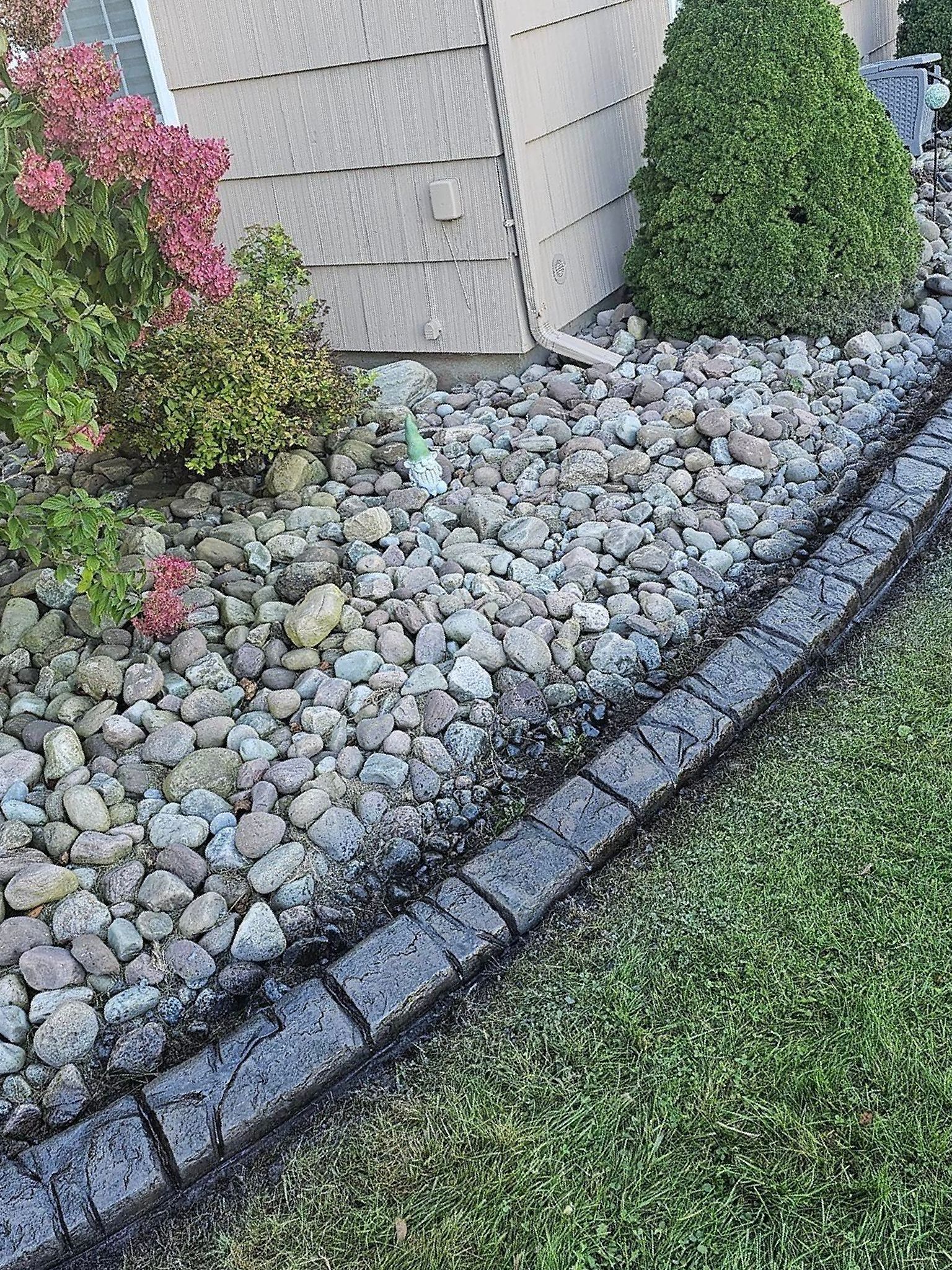 A stone path in a park surrounded by trees and bushes.