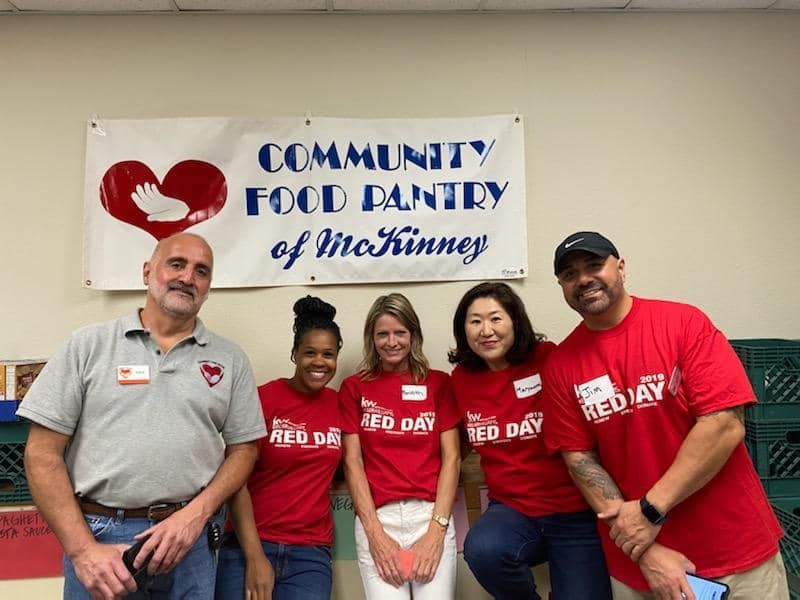 A group of people are posing for a picture in front of a community food pantry sign.