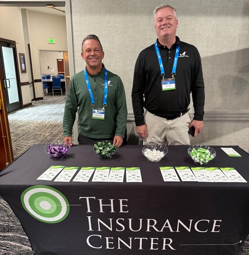 Two people shaking hands in a bright, modern office as a third person smiles and looks on.