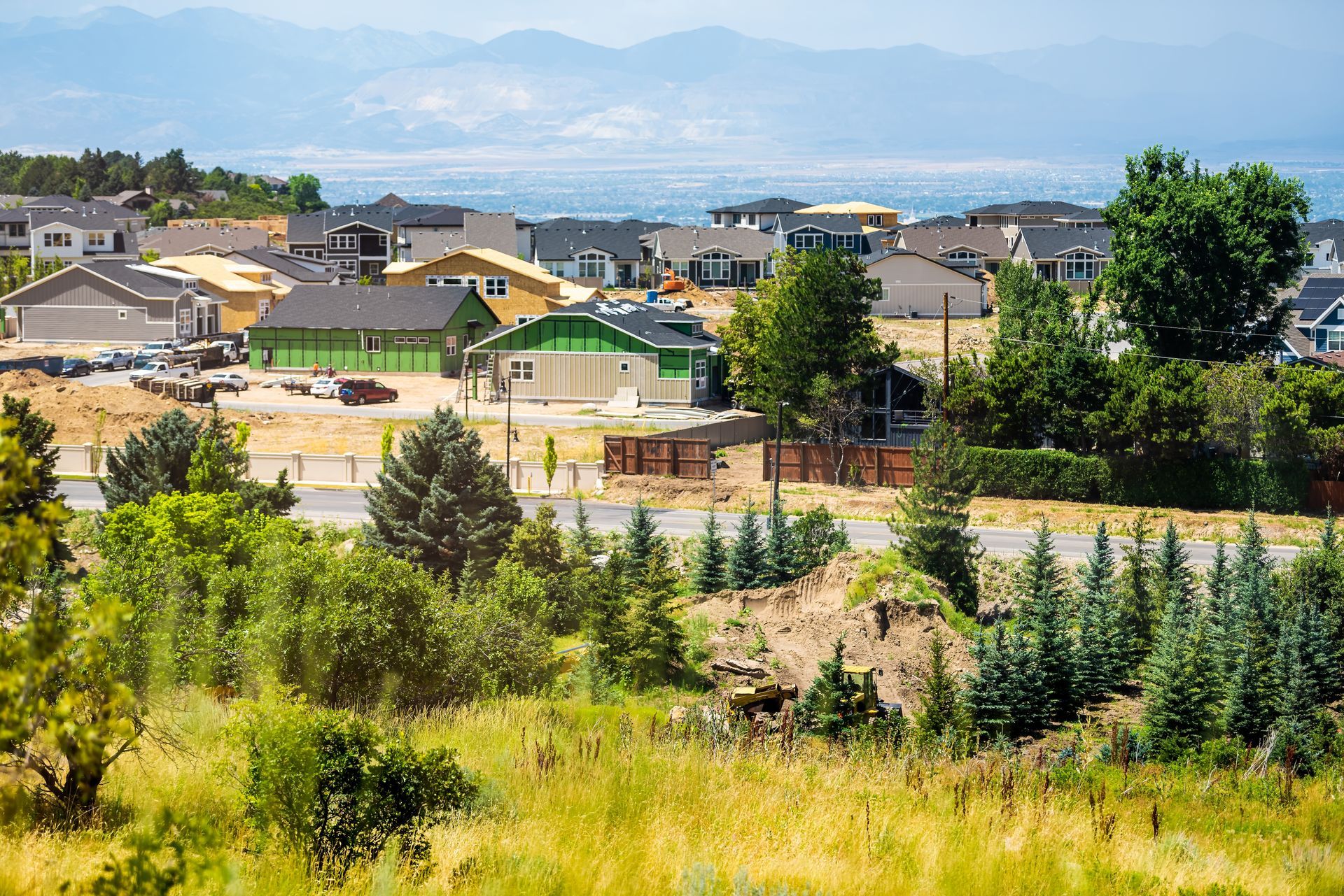 A residential neighborhood under construction sits on a hill with distant mountains in the background.