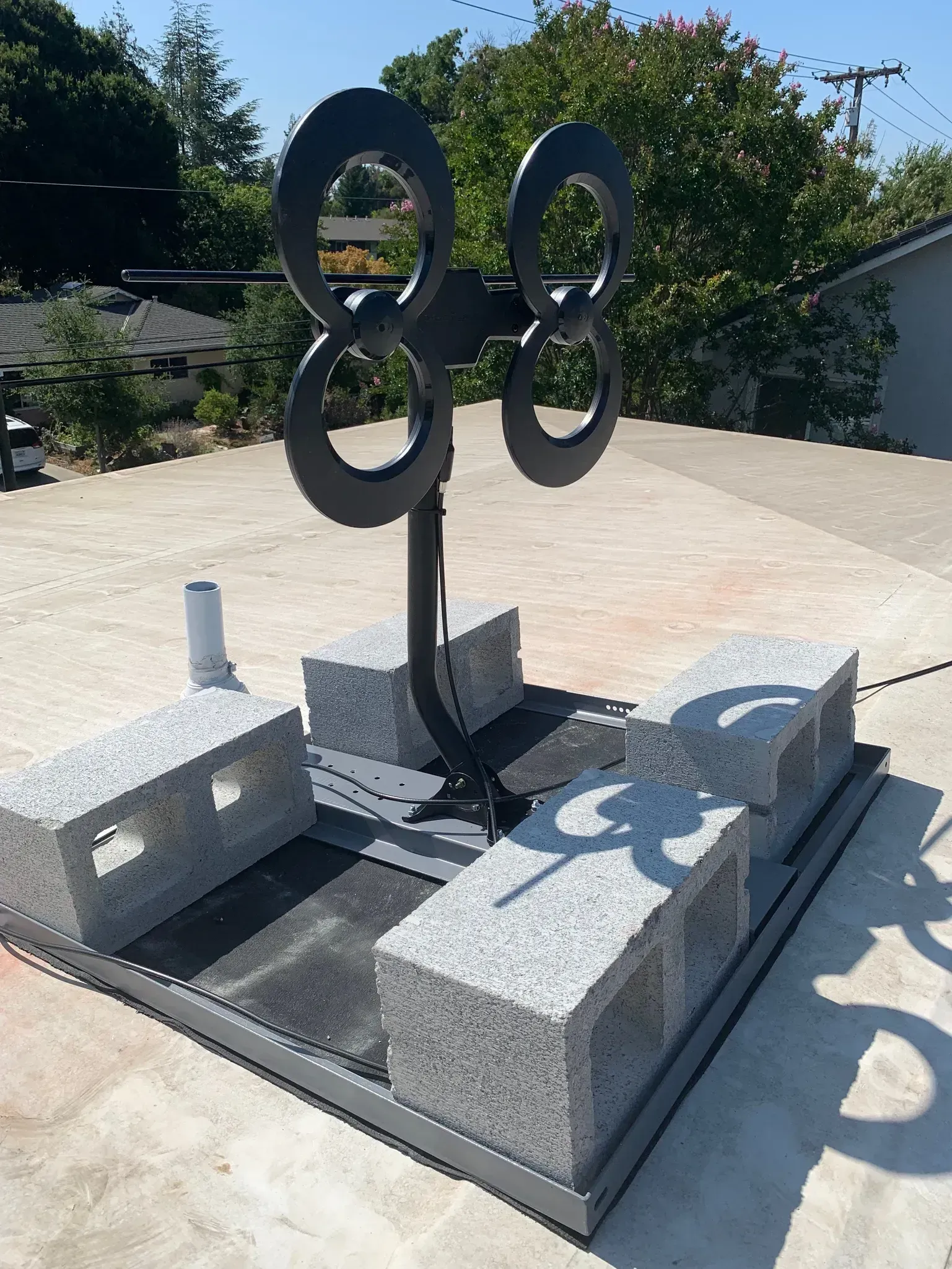 A black sculpture is sitting on top of a concrete block in a parking lot.