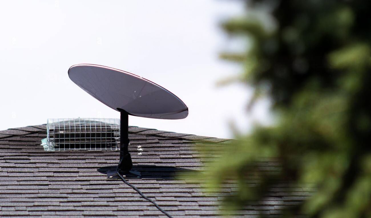 A satellite dish is sitting on top of a roof.