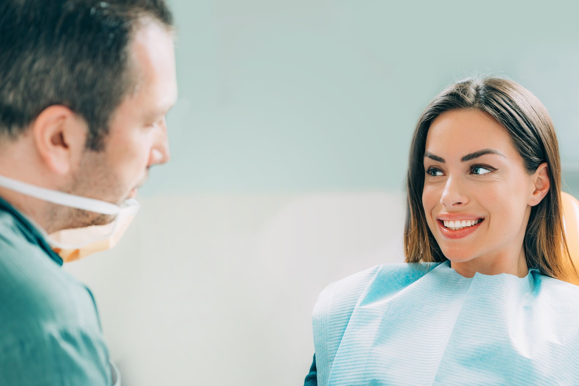 A happy patient smiling during a consultation with an expert cosmetic dentist in a modern office.