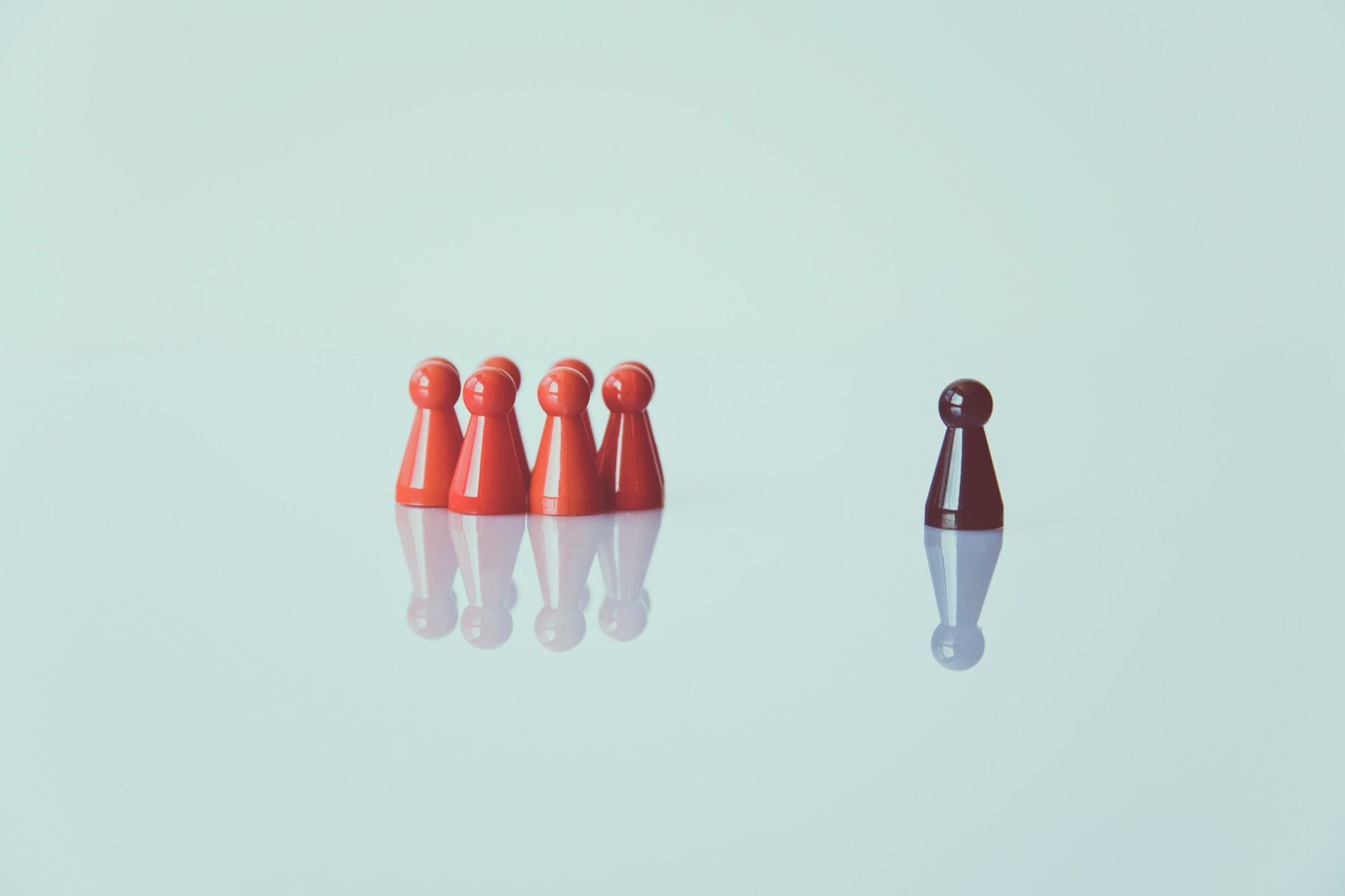 Five red bowling pins grouped together and one separate pin on a light background.