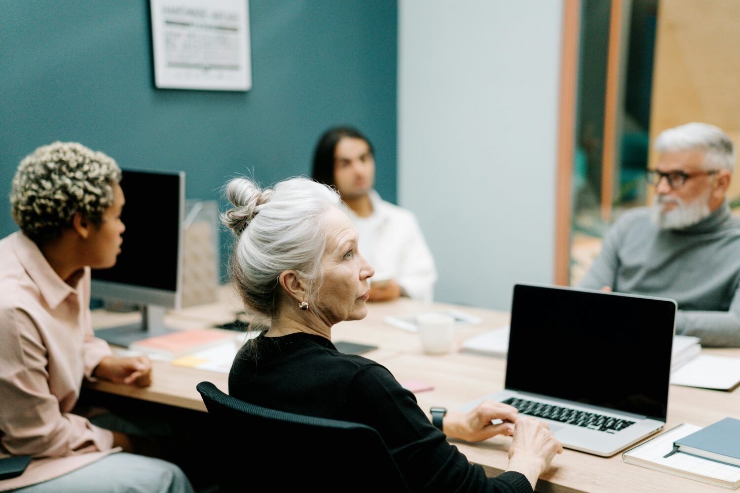 People in a conference room discussing around a table with a laptop open in the foreground