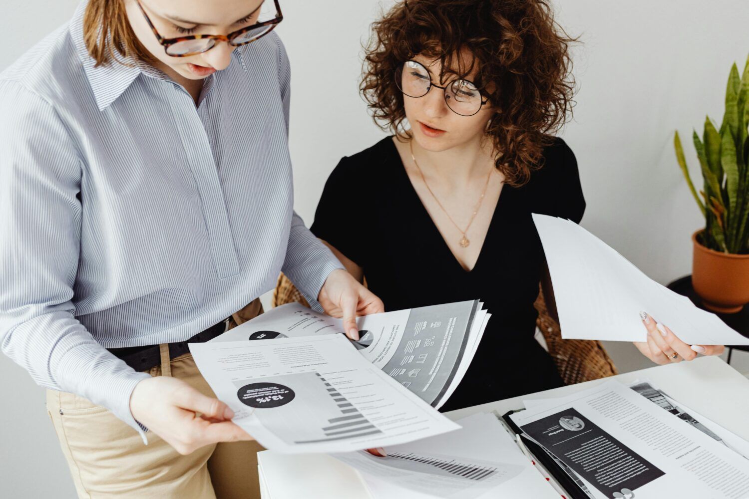 Two coworkers reviewing printed charts at a desk in a bright office